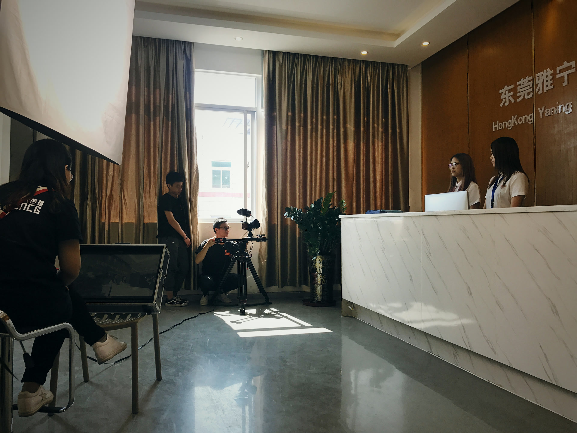 客户前台那场戏,摄影蹲在柜台侧面找角度,监视器支在大厅另一头,两个前台站在原位等光。